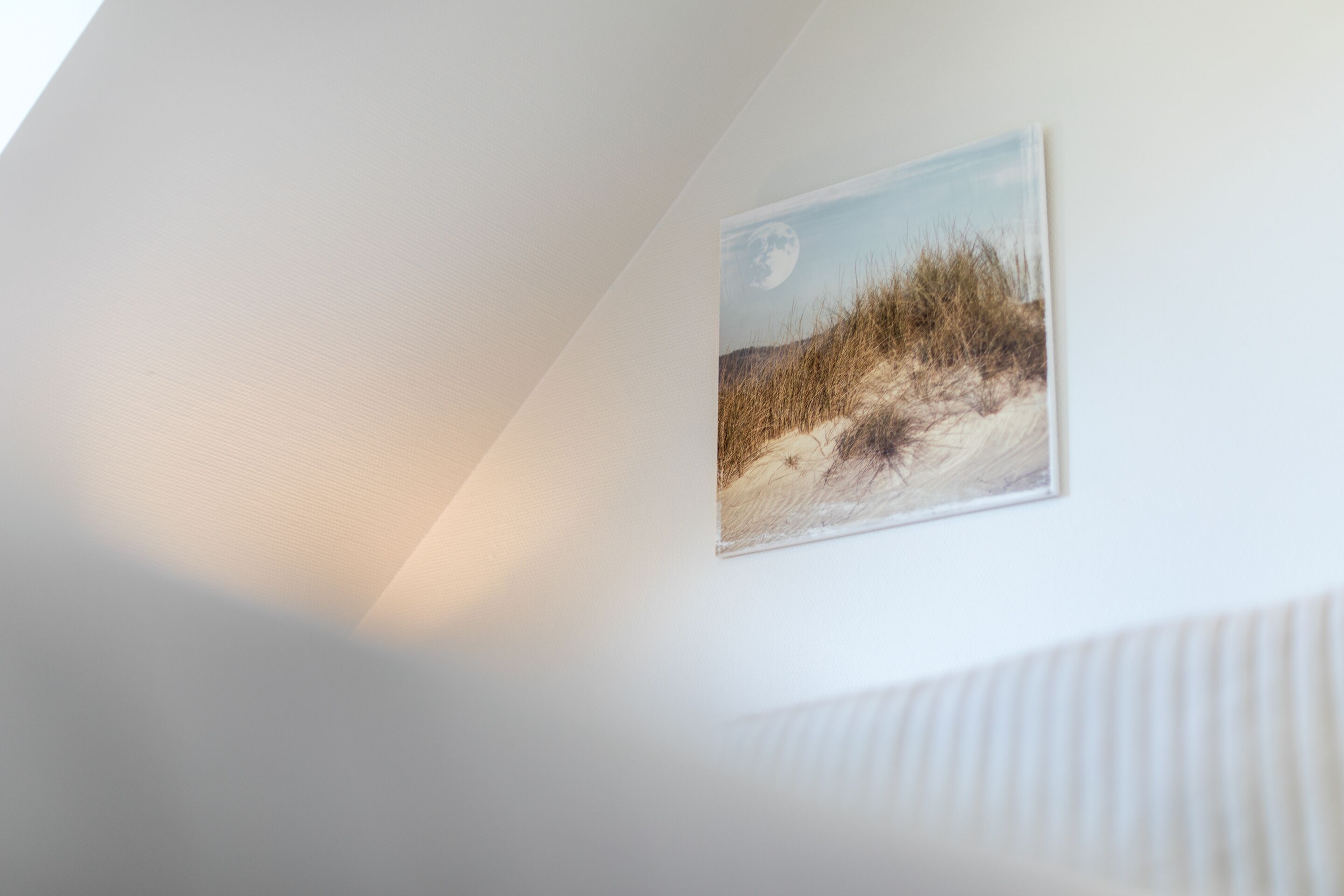 Un mur orné d’un tableau représentant une scène de plage.