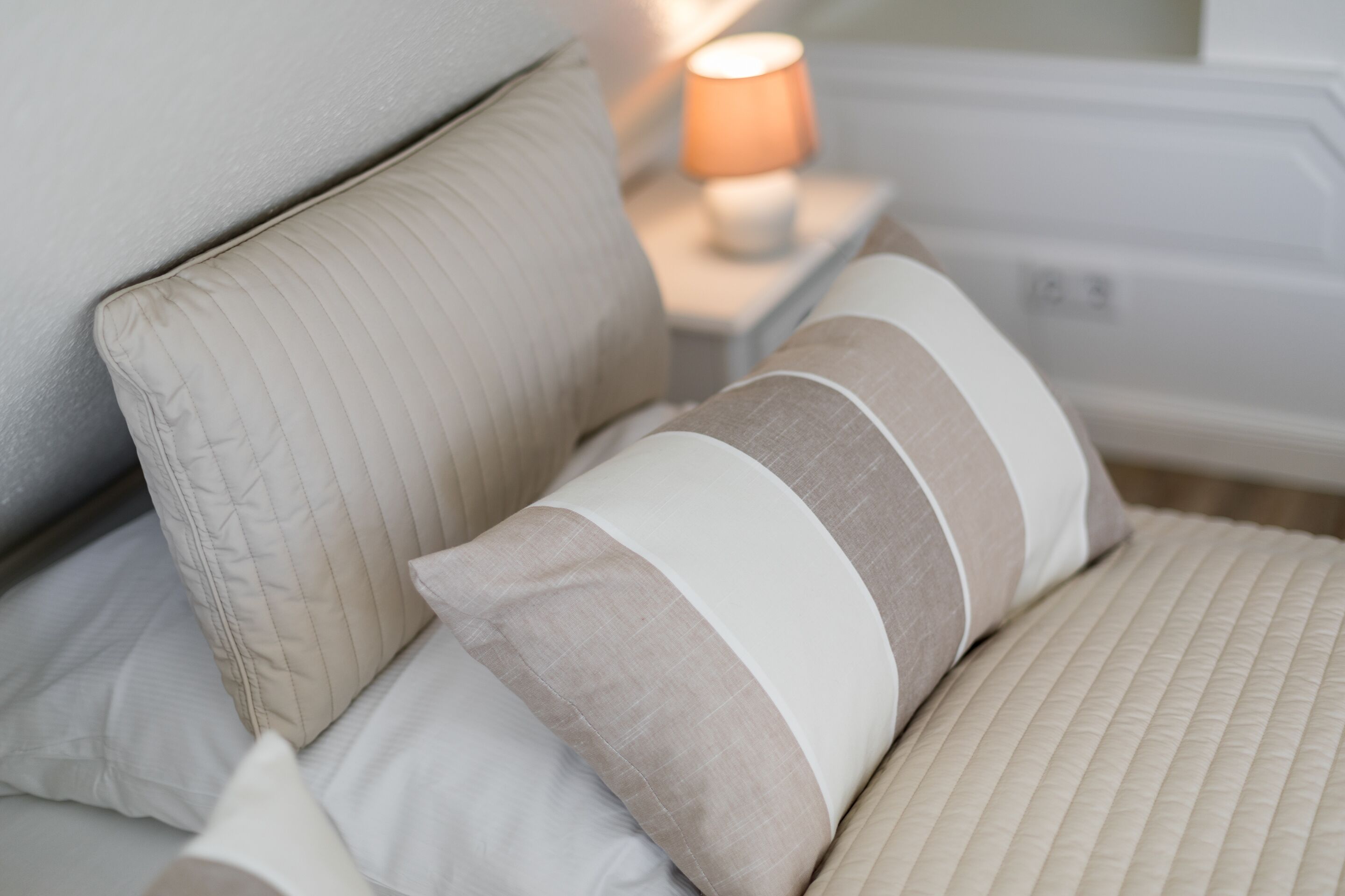 A bed with multiple pillows and a bedside lamp.
