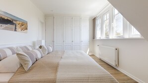 Quarto com uma cama grande, janela com vista e guarda-roupa branco.