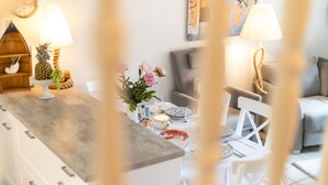 Une cuisine moderne avec des meubles blancs, un plan de travail en bois et un coin repas comprenant des chaises blanches et une table dressée pour deux personnes.