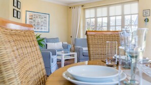 A dining area with wicker furniture, a white coffee table, and a window with curtains. - Zentral, Aber Dennoch Sehr Ruhig und Strandnah Gelegen (Wenningstedt-Braderup (Sylt))
