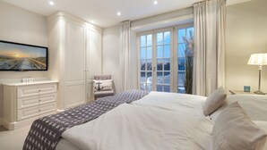 Une chambre à coucher avec un grand lit, un téléviseur fixé au mur, un bureau et une chaise.
