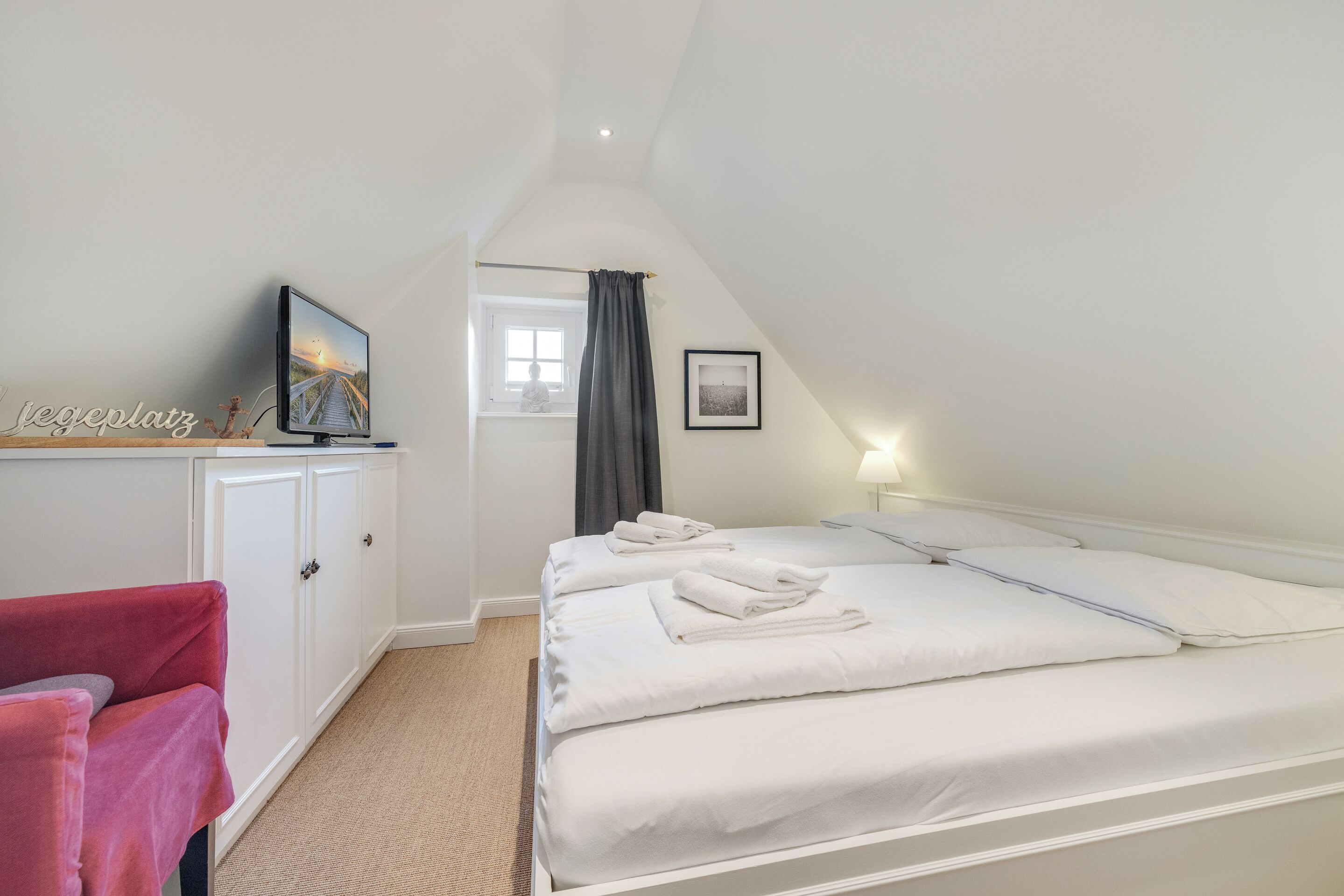 Ein Schlafzimmer mit Bett, Schreibtisch, Stuhl, Fenster und einem Bild an der Wand.