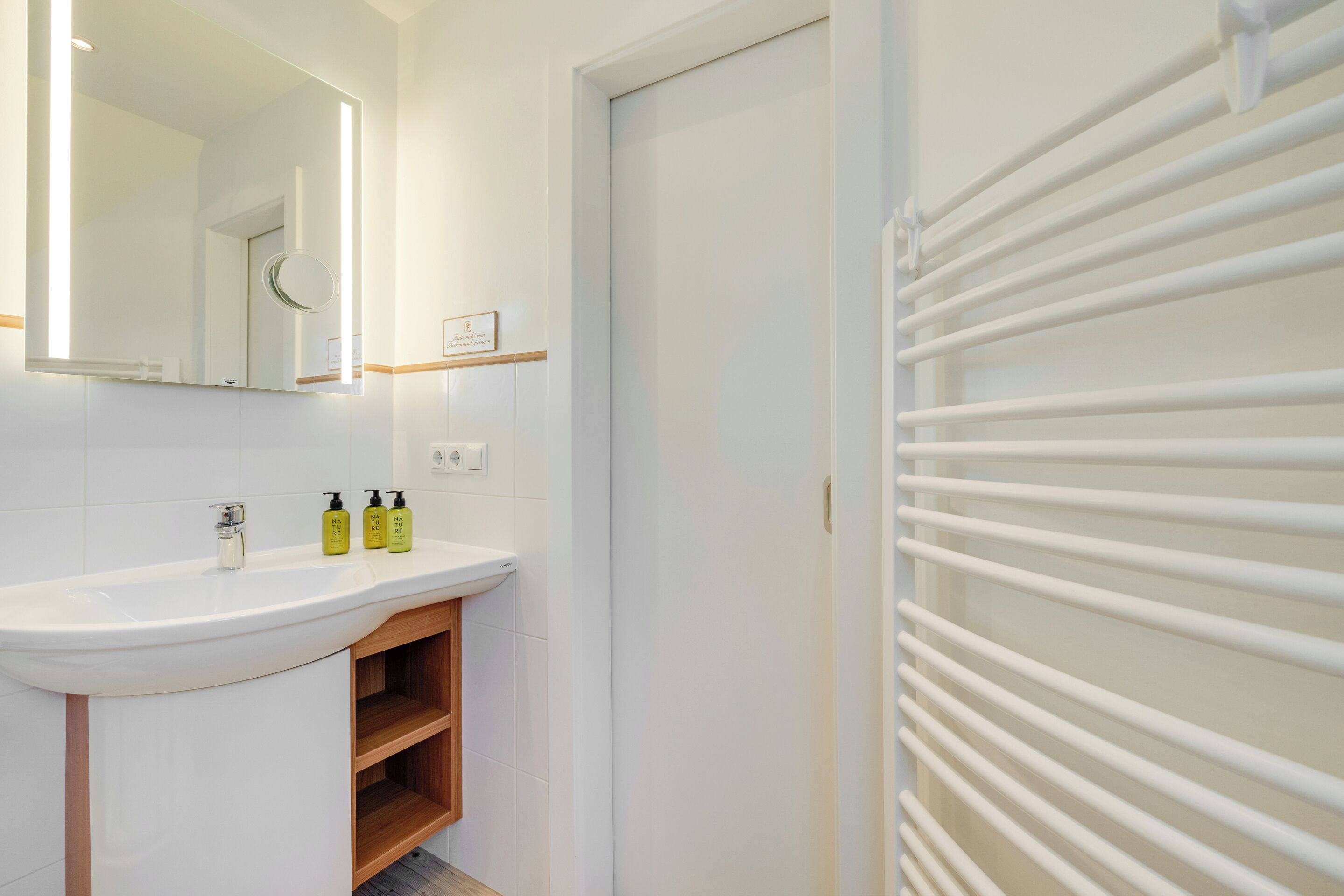 Une salle de bain avec un lavabo blanc, un miroir et un porte-serviettes.