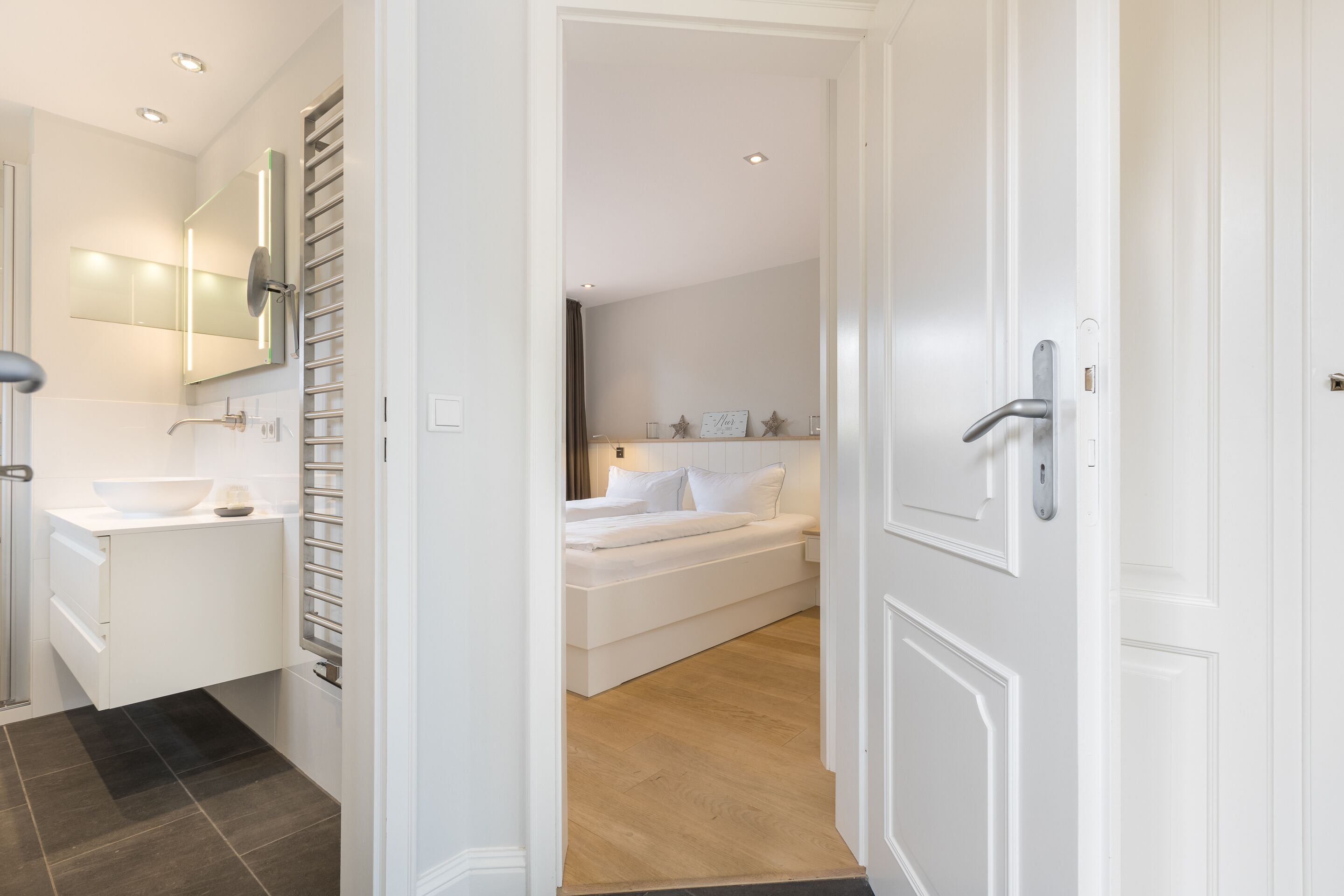 A modern bathroom with a white sink, mirror, and towel rack.