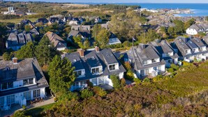 A coastal residential area with houses featuring pitched roofs and a mix of single and two-story buildings.