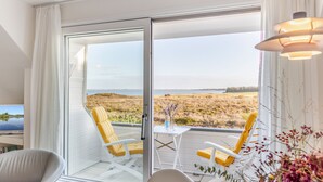A room with a sliding glass door leading to a balcony with yellow chairs and a small table.