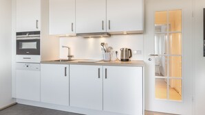 A modern kitchen with white cabinets, stainless steel appliances, and a wooden countertop.