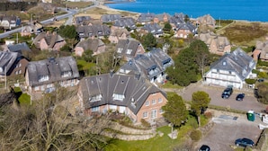 A coastal residential area with houses, a road, and a pier.
