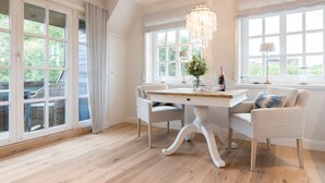 A dining area with a white table, two chairs, and a chandelier.