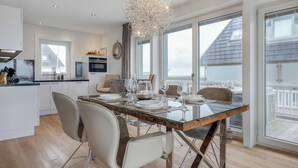 A modern kitchen with white cabinets, a built-in oven, and a dining area with a glass table and chairs.