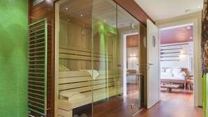 Una habitación moderna con un vestidor amplio con puertas de vidrio, suelo de madera y un banco.