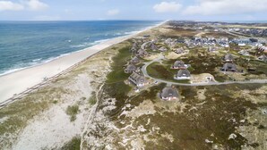 Vista aérea de un pueblo costero con casas, una playa y un cielo despejado.