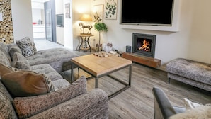 Ein modernes Wohnzimmer mit Kamin, Flachbildfernseher und einer gemütlichen Sitzecke.