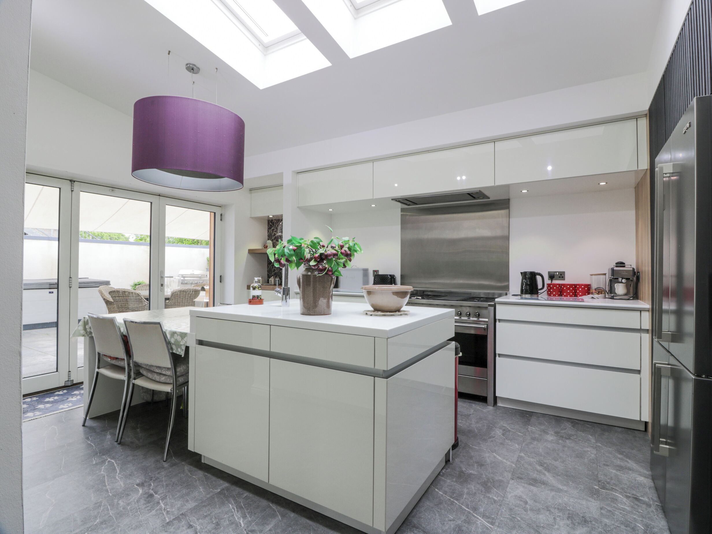 A modern kitchen with a central island, a large window, and a skylight.