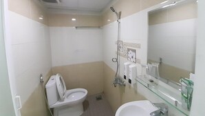 A small, compact bathroom with a toilet, a glass shower enclosure, a sink, and a mirror. - Capital O 1221 Thien An Hotel (Ho Chi Minh City)