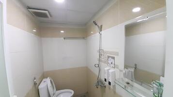 Un baño pequeño y funcional con inodoro, cabina de ducha de vidrio, lavabo y espejo.