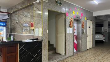 Zona de recepción de un hotel con un mostrador de mármol, un refrigerador de Pepsi y un coche estacionado afuera.