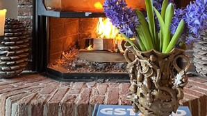 Una chimenea con un marco de piedra decorativo, una repisa de madera y un jarrón con flores.