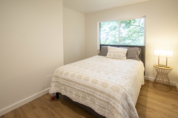 A bedroom with a bed, a window, and a bedside lamp.
