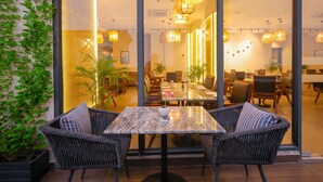A modern dining area with wicker chairs, a marble table, and warm lighting. - Rhythm Gurugram, Hotel & Suites, Sohna Road - Sector 68 (Gurugram)