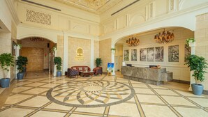 A hotel lobby with a central circular floor design, a reception desk, seating area, and decorative chandeliers. - Rhythm Gurugram, Hotel & Suites, Sohna Road - Sector 68 (Gurugram)