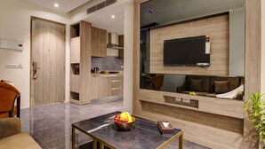 A modern living room with a TV, a dining area, and a kitchen. - Rhythm Gurugram, Hotel & Suites, Sohna Road - Sector 68 (Gurugram)