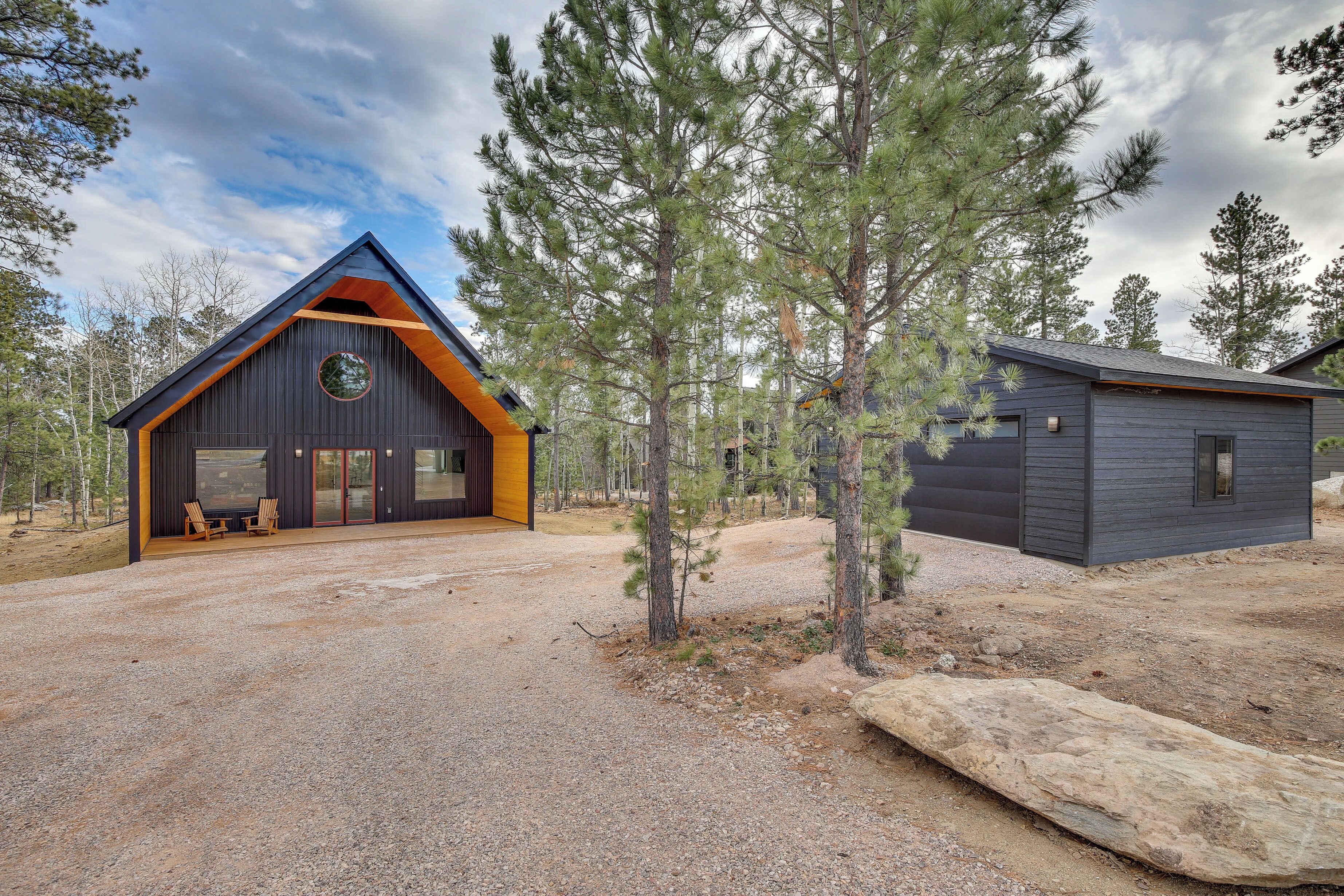 A modern cabin with a large front porch and a separate garage.