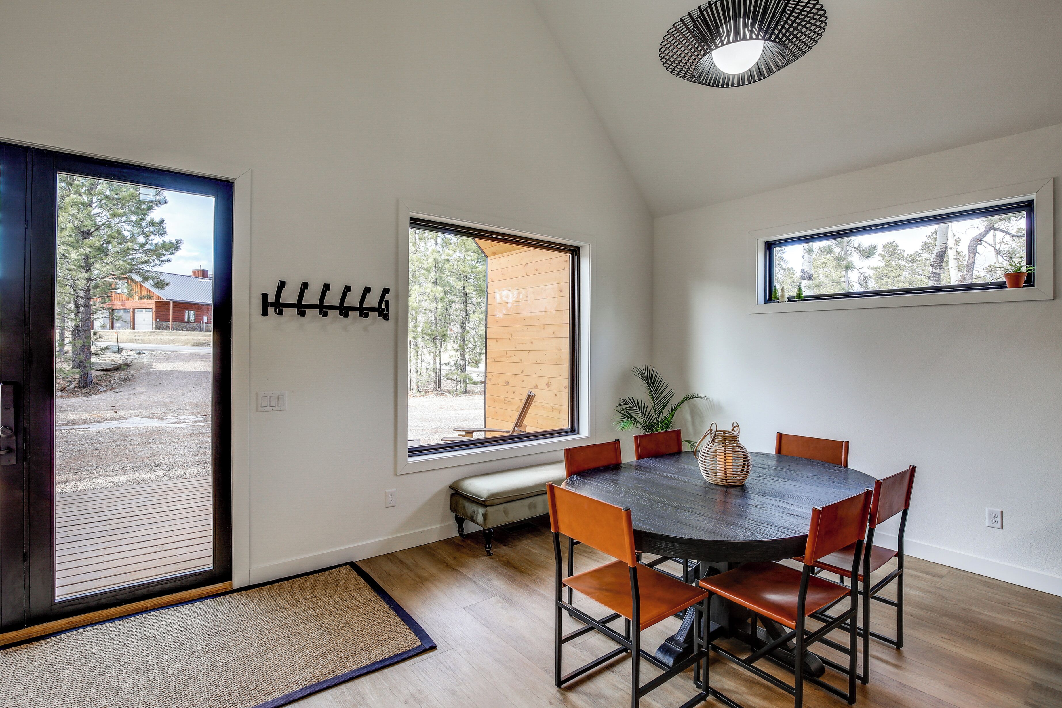 A dining area with a dark wooden table, orange chairs, and a view of the outdoors through large windows.