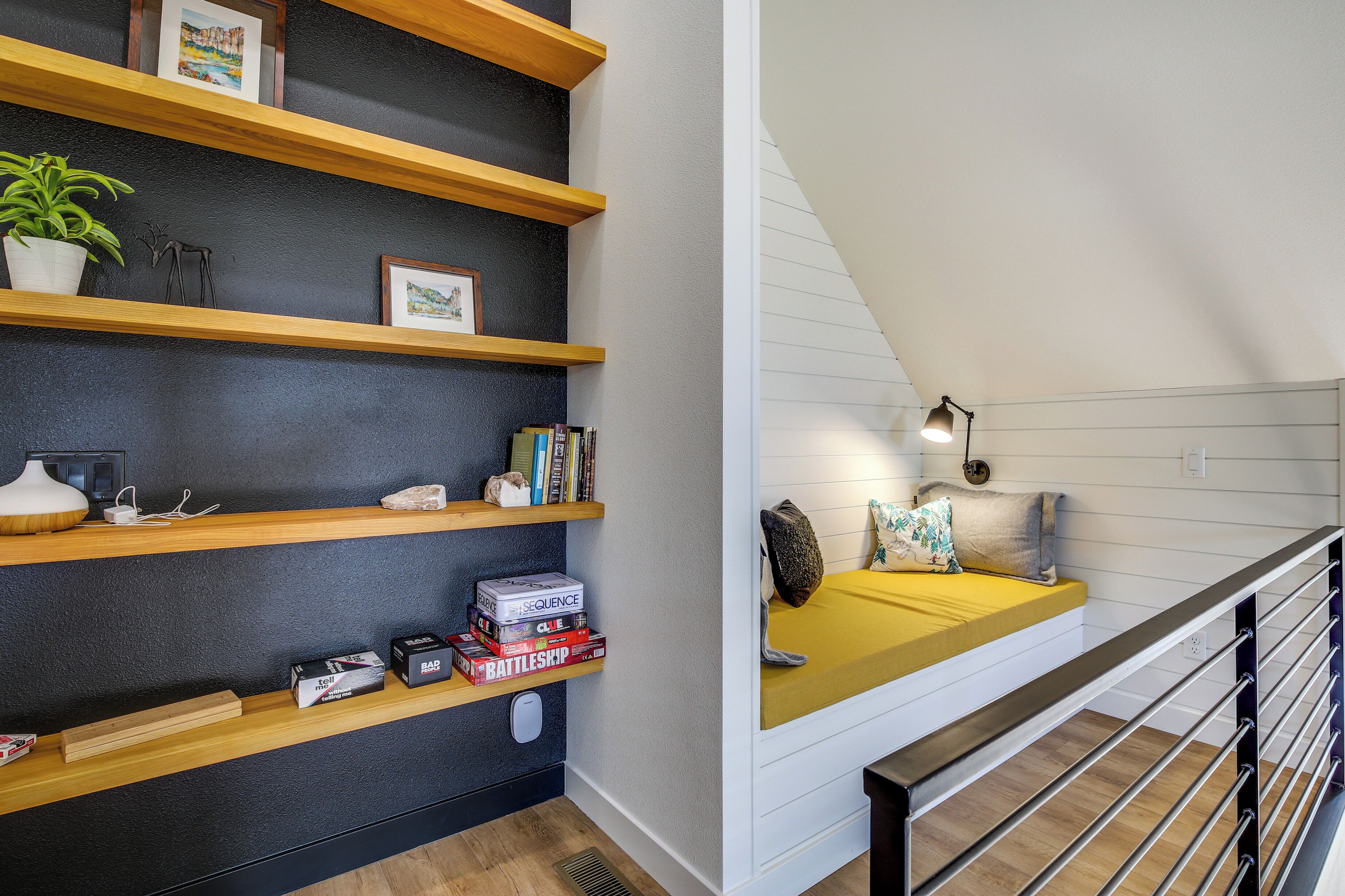 Ein modernes Schlafzimmer im Loft-Stil mit schrägverdeckter Decke, einer Holztreppe und einer eingebauten Bücherreolen.