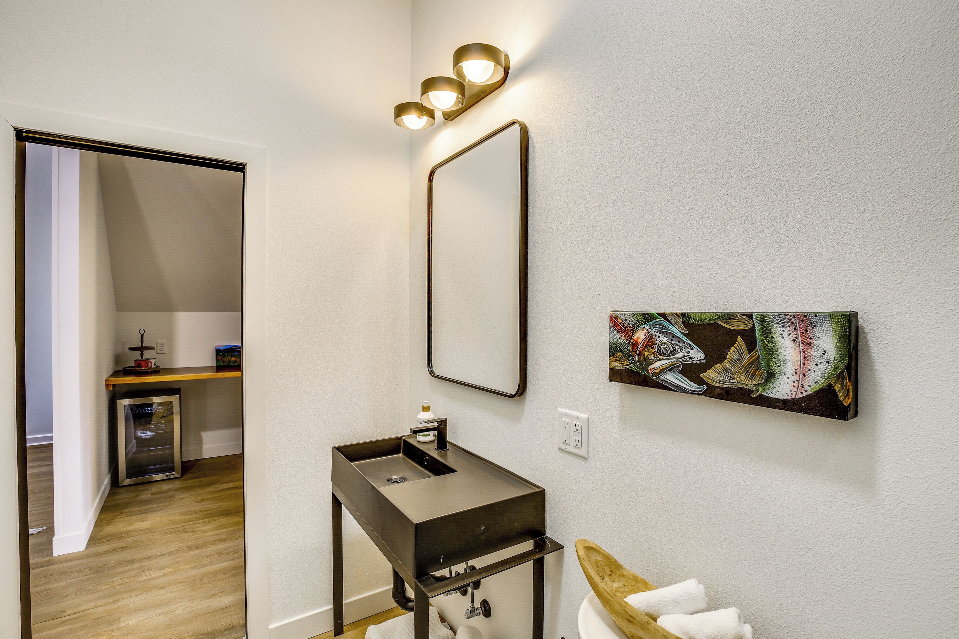 A bathroom with a modern sink, a mirror, and a wall-mounted light fixture.