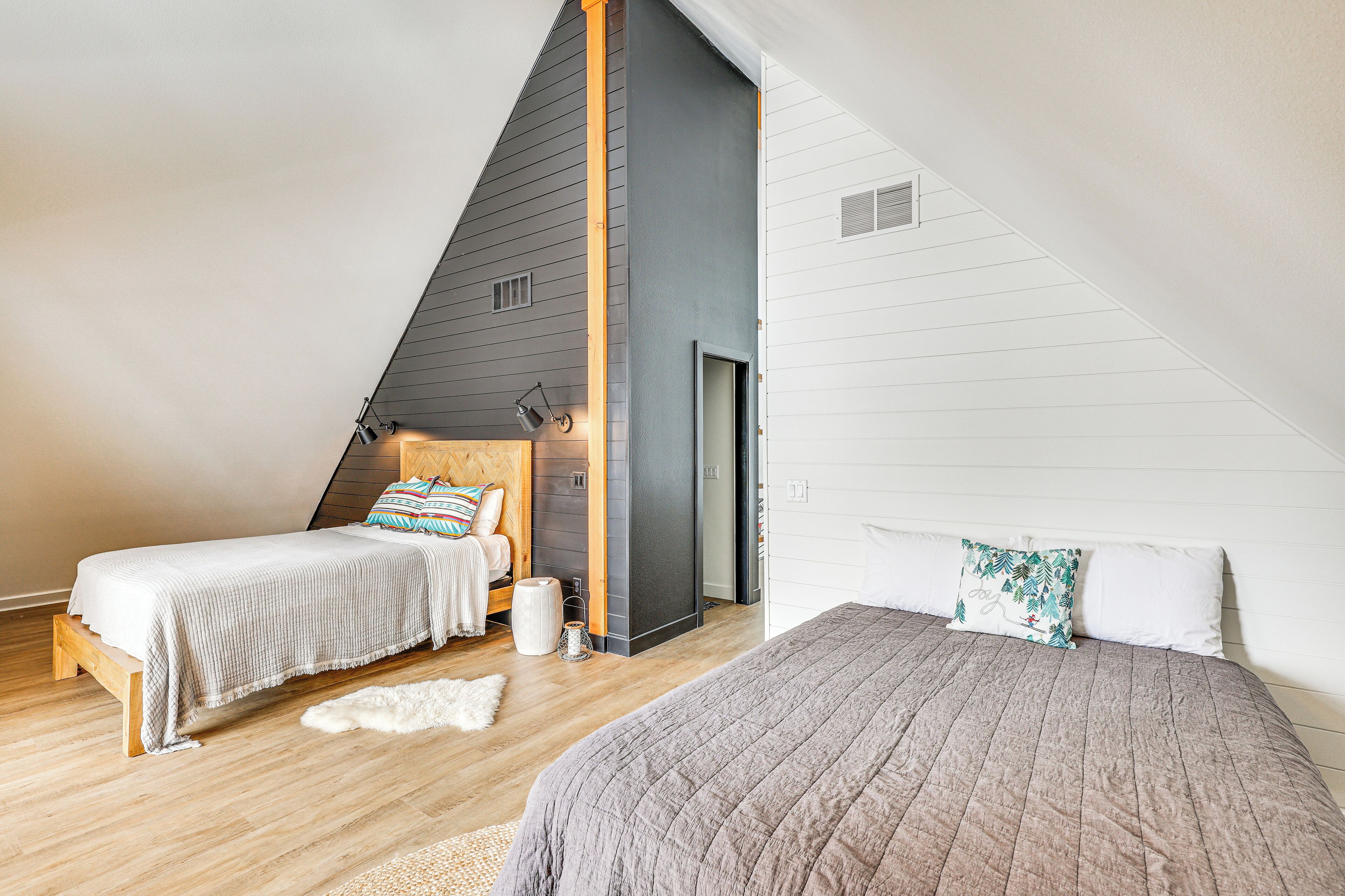 A bedroom with two beds, wooden flooring, and a sloped ceiling.