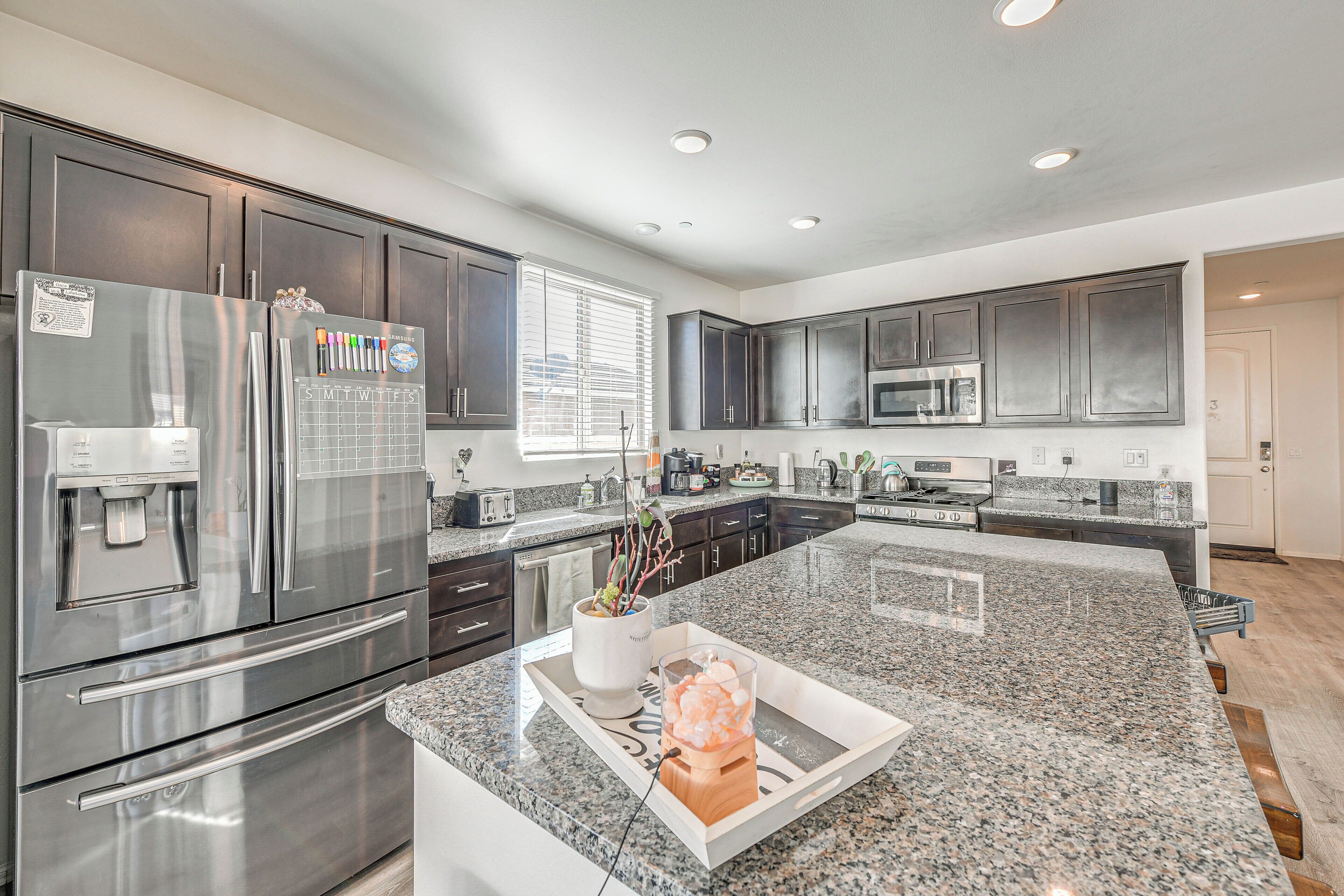 A modern kitchen with stainless steel appliances, granite countertops, and dark cabinetry.