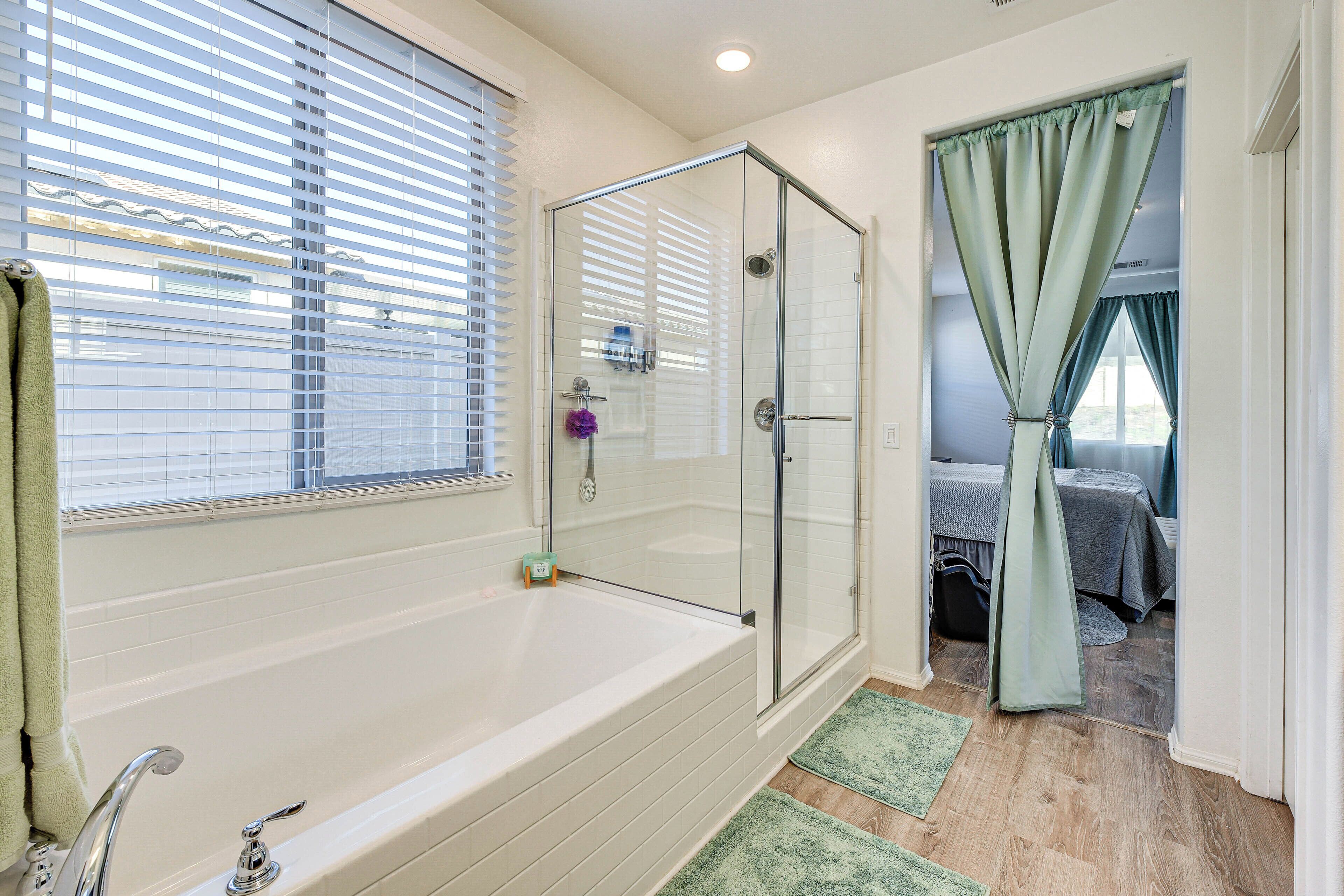 Une salle de bain avec une douche à parois de verre, une baignoire et une fenêtre équipée de stores.