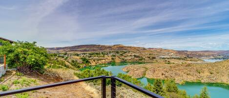 Vista panorámica desde un balcón con vista a un valle fluvial y colinas distantes bajo un cielo despejado.