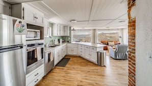 Una cocina moderna con armarios blancos, electrodomésticos de acero inoxidable y suelo de madera.