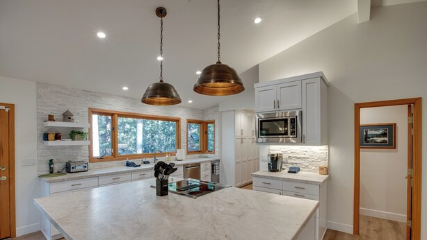 A spacious kitchen with a large island, white cabinetry, and a view of trees through the windows. - 4 Mi to Slopes: Family-friendly Stateline Home! (Stateline)