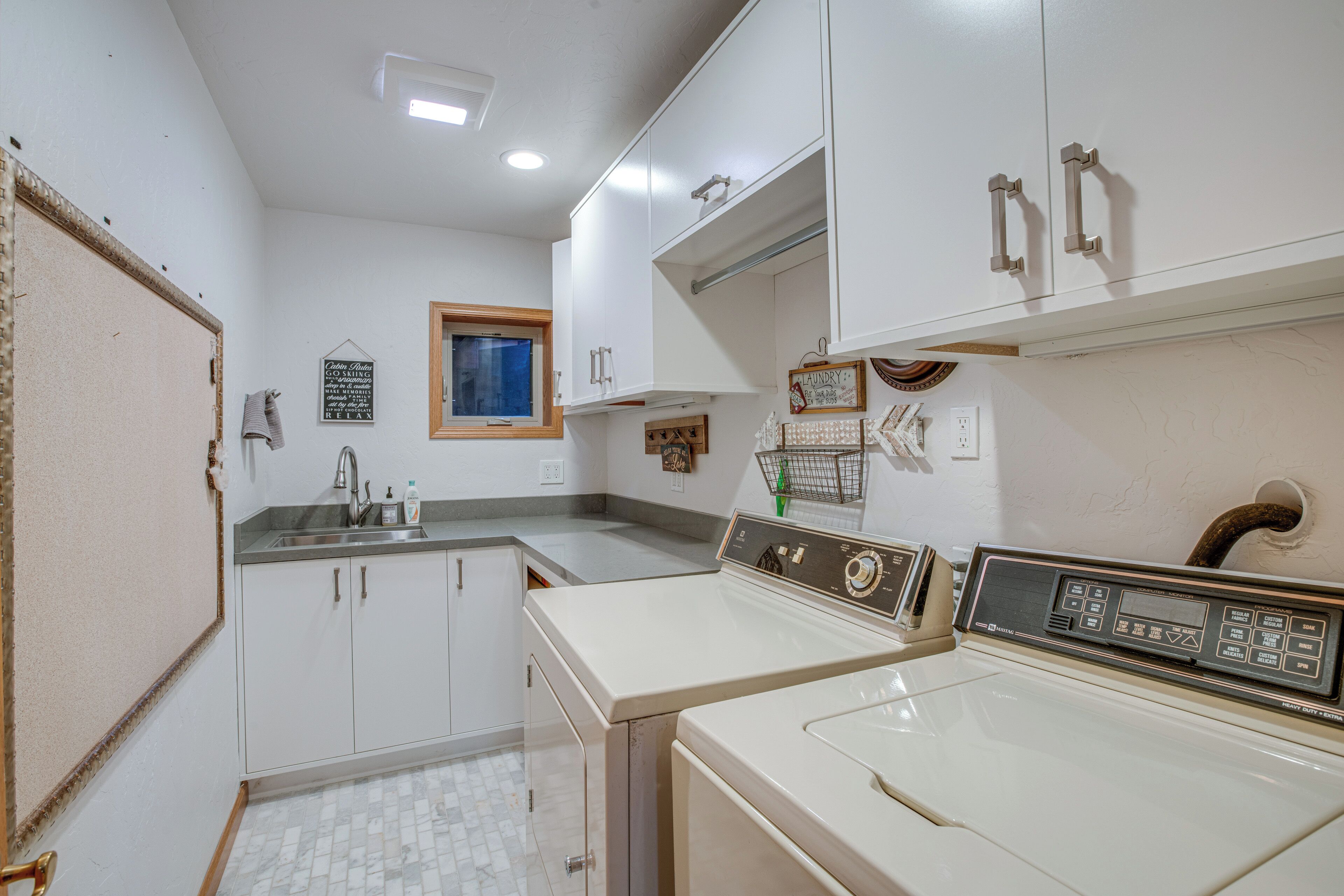 A compact kitchen with white cabinets, a sink, and a vintage washing machine.