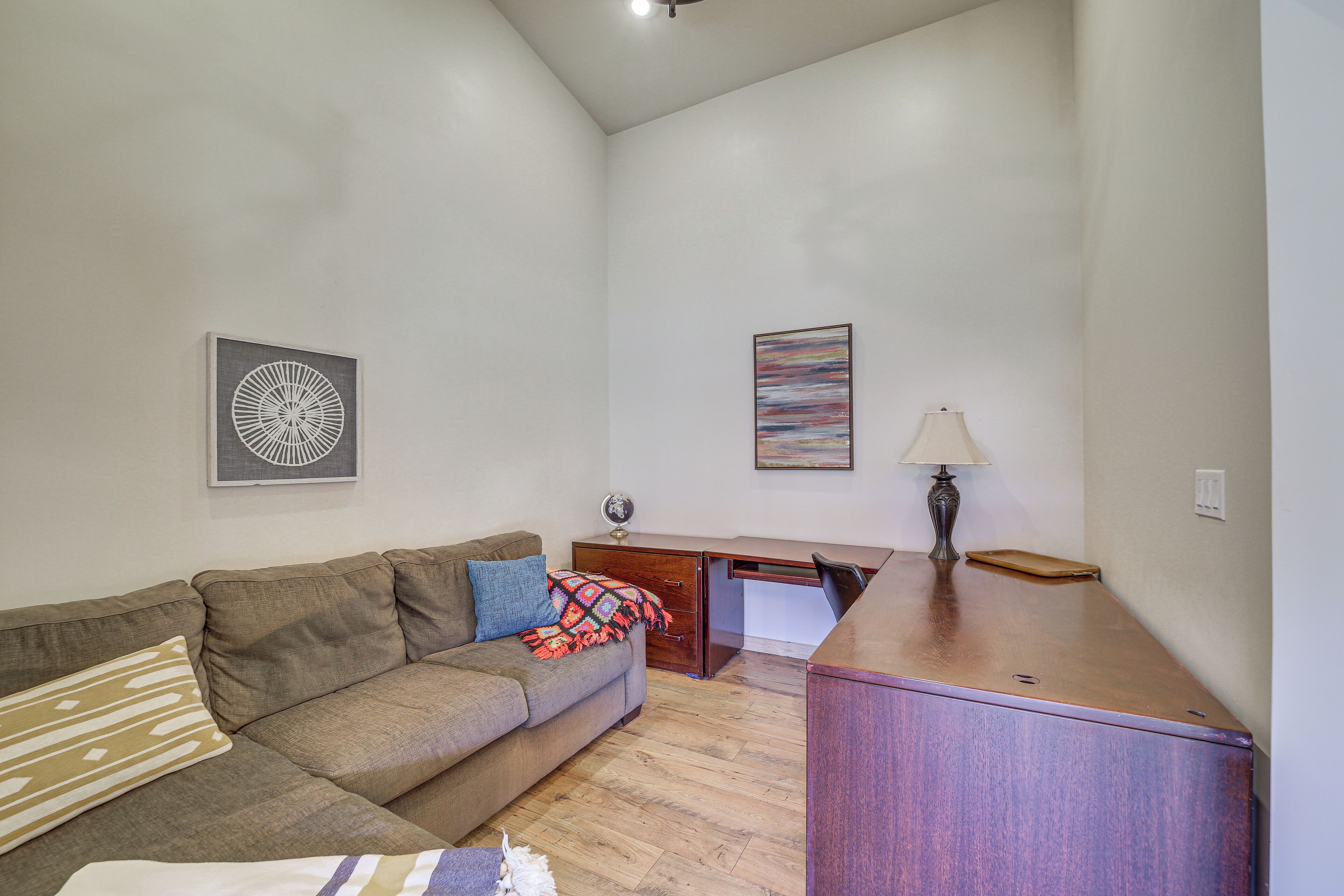 A living room with a sofa, a desk, and a lamp.