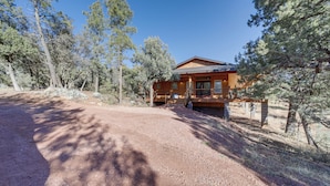 A wooden cabin with a covered porch, surrounded by pine trees and a dirt path. - 'lavender Lodge' Mountain-view Pine Cabin w/ Deck (Pine)