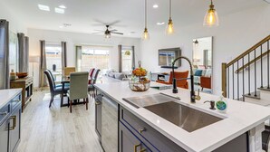 A modern kitchen with a central island, pendant lighting, and a view to the living area. - Modern Houston Retreat w/ Patio, 11 Mi to Dtwn (Houston)