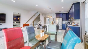A modern kitchen with dark blue cabinets, a stainless steel refrigerator, and a dining area with glass tables and chairs. - Modern Houston Retreat w/ Patio, 11 Mi to Dtwn (Houston)