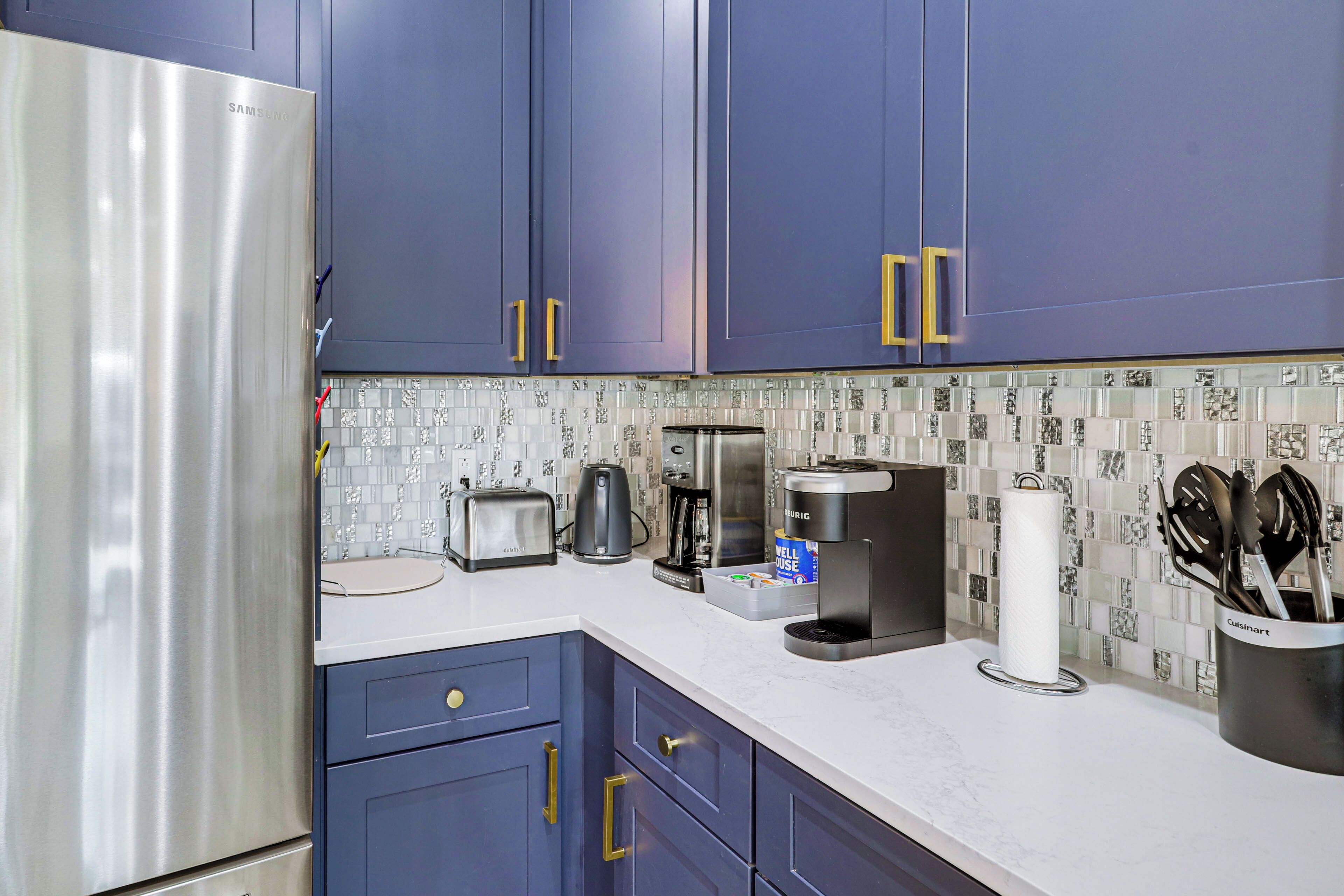 A modern kitchen with stainless steel appliances, blue cabinets, and a patterned backsplash.