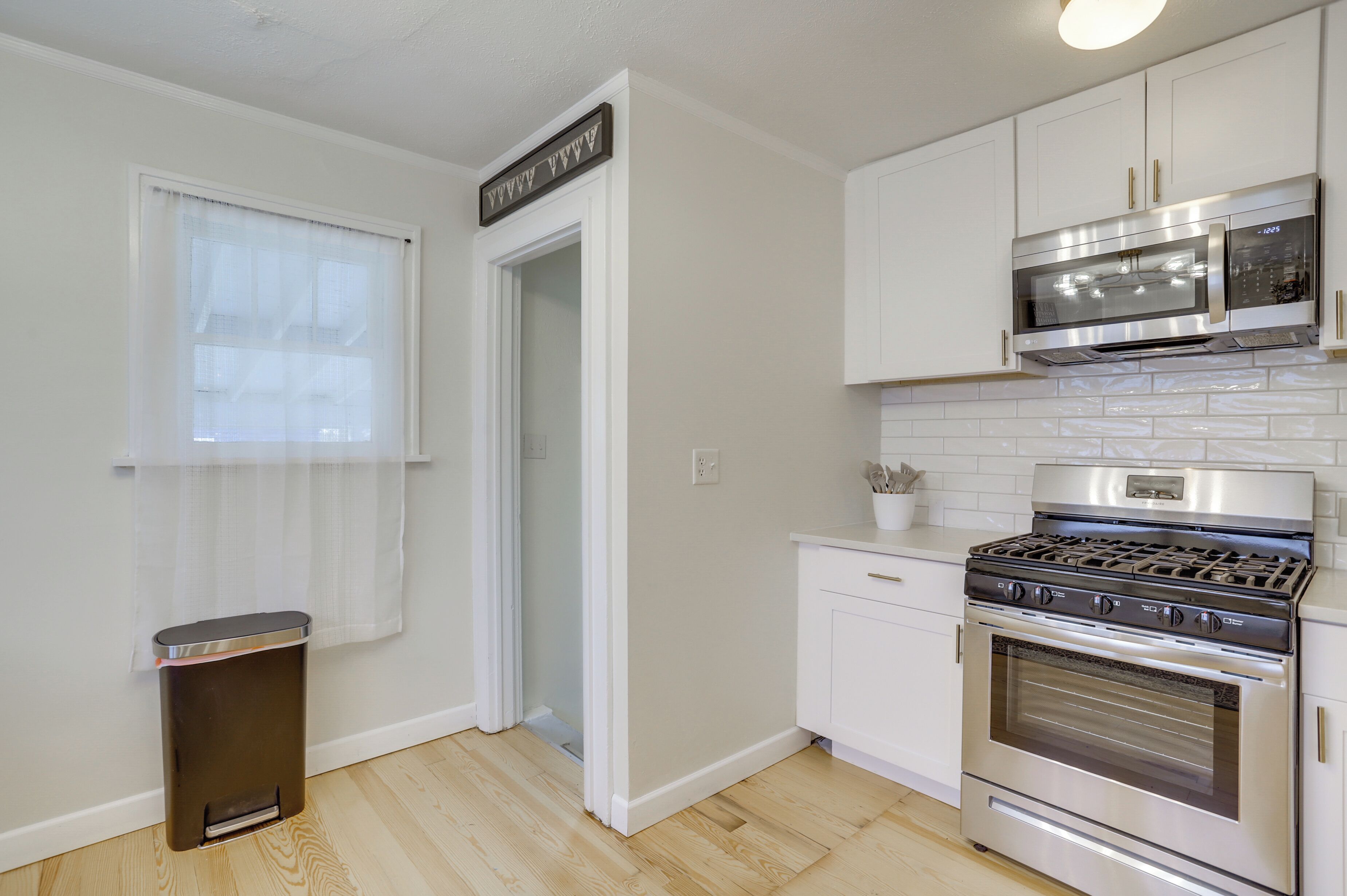 A kitchen with white cabinets, a stainless steel stove, and a microwave above it.