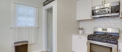 A kitchen with white cabinets, a stainless steel stove, and a microwave above it.