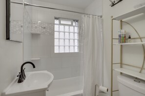 Un baño moderno con un lavamanos blanco, una ducha con puerta de cristal y una ventana con vistas.