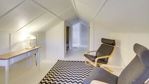 Una habitación moderna y bien iluminada con una consola de madera, una alfombra blanco y negro y un sillón de cuero.