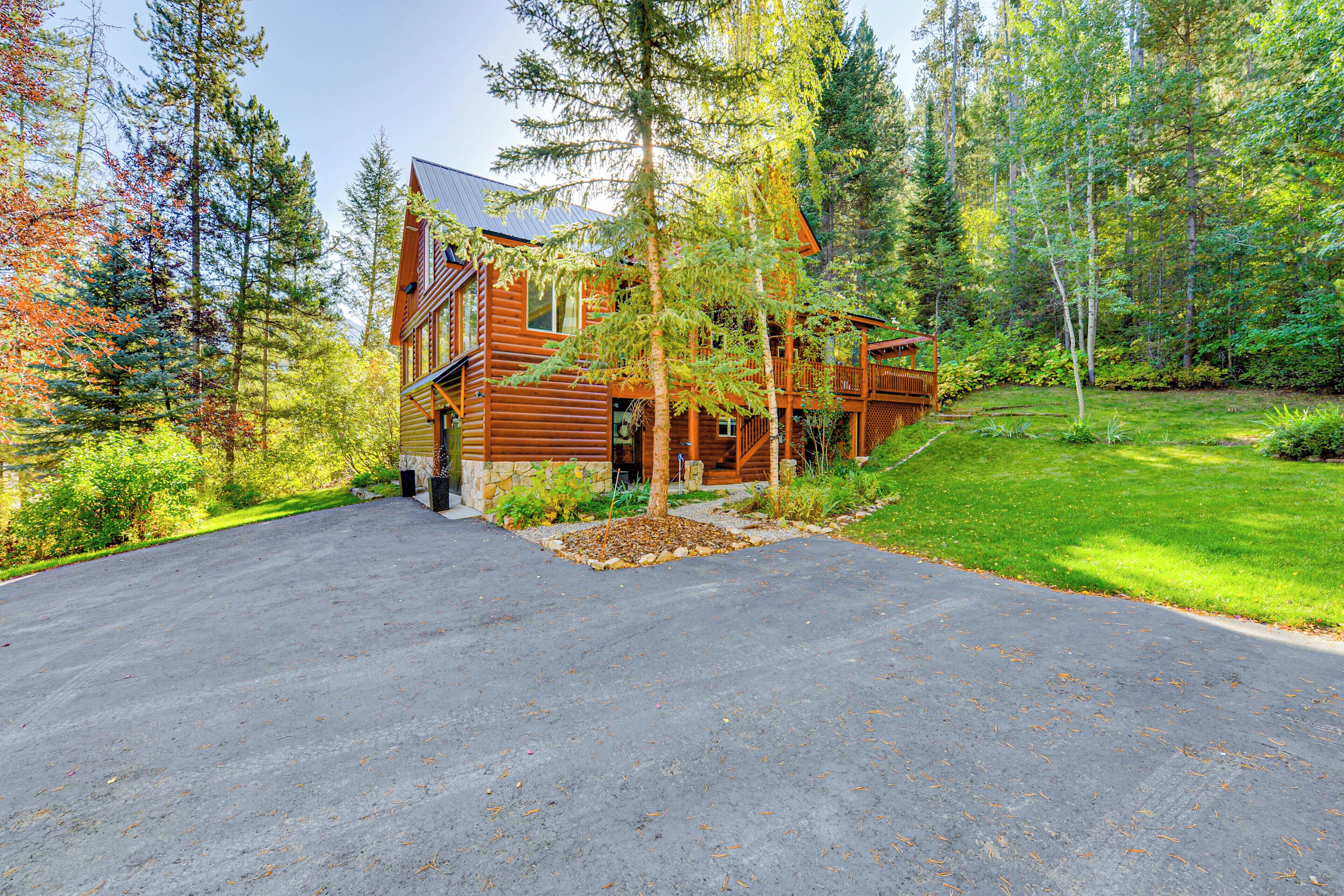 A log cabin with a paved driveway and a well-maintained lawn.