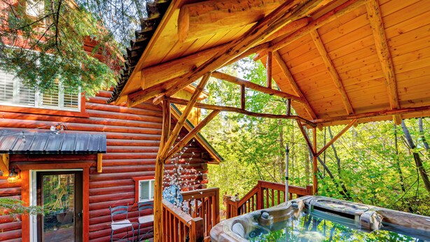 A log cabin with a hot tub and outdoor seating area.