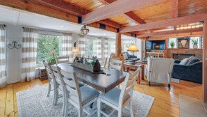 A spacious dining area with a wooden table and chairs, a fireplace, and a cozy seating area with a sofa and armchairs.
